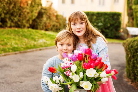 Ittle boy and his big sister holding big beautiful bouquet of colorful tulipsの写真素材