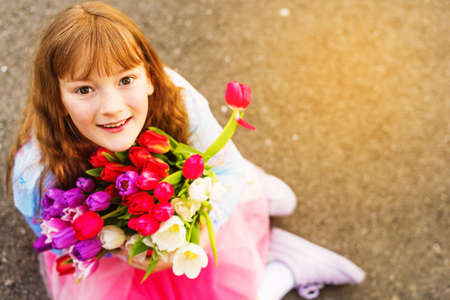 Outdoor portrait of a sweet kid girl with big bouquet of colorful tulipsの写真素材