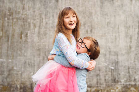 Outdoor portrait of two funny fashion kids, holding drinks, wearing blue and pink clothesの写真素材