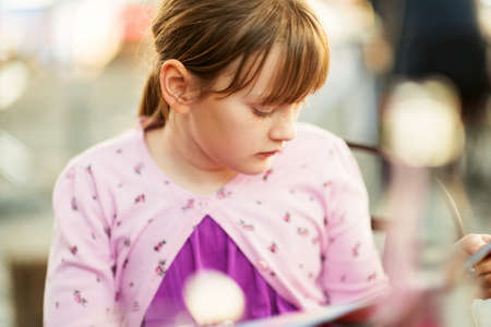 Kid girl choosing menu in the restaurantの写真素材