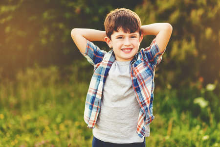 Happy kid boy of 6 year old having fun outdoors wearing blue plaid shirt