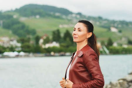Outdoor portrait of beautiful brunette woman, wearing brown leather jacketの写真素材