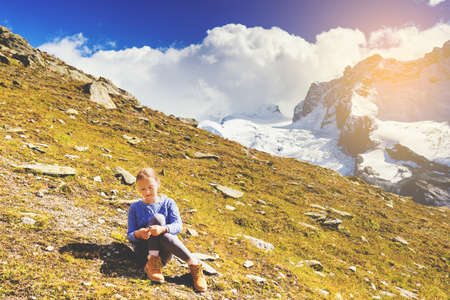 Cute little girl wearing blue pullover and beige boots, resting in mountains, Switzerlandの写真素材
