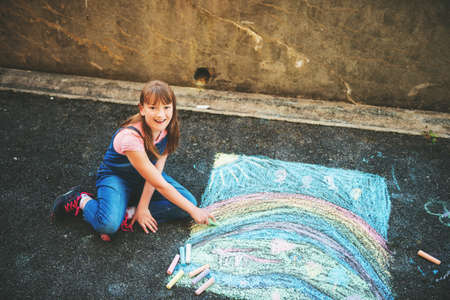 Adorable little kid girl drawing with chalk outdoors, top viewの写真素材