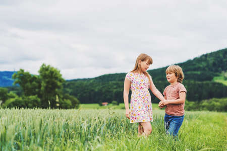 Two adorable kids playing together in summer wheat fieldの写真素材