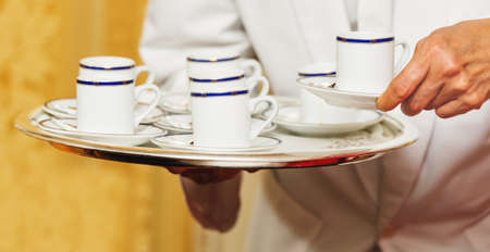 Waiter carrying tray with coffee cups on some festive event, party or wedding reception