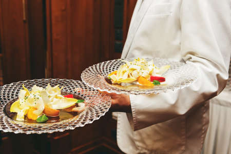 Waiter carrying plates with salad on some festive event, party or wedding receptionの写真素材