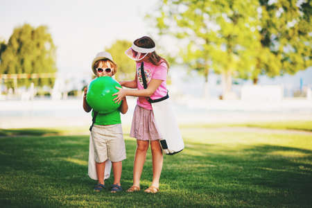 Two funny kids in green park. Little boy and girl ready to go to the pool on a hot summer dayの写真素材
