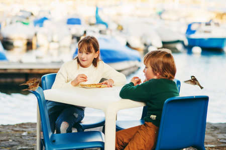 Cute little kids eating pancakes in a cafe, feeding birdsの写真素材