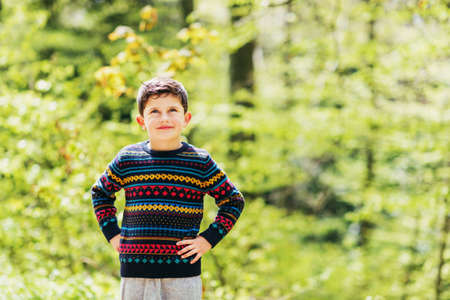 Cute little boy enjoying fresh spring forest, wearing warm colorful pulloverの写真素材
