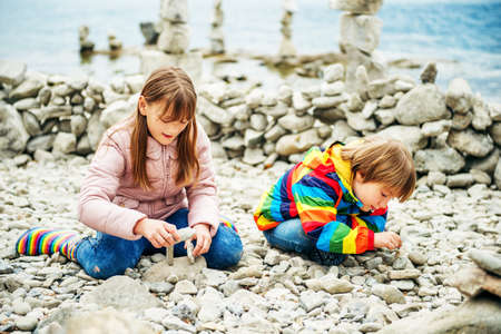 Kids playing between stacks of stones on the beachの写真素材