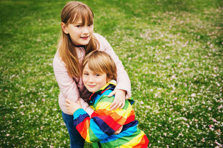 Spring portrait of adorable siblings, little boy and girl playing together outsideの写真素材