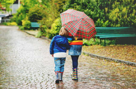 Two kids under umbrella, back viewの写真素材