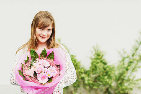 Close up portrait of adorable brown hair kid girl holding big flower bouquet with roses, film look imageの写真素材