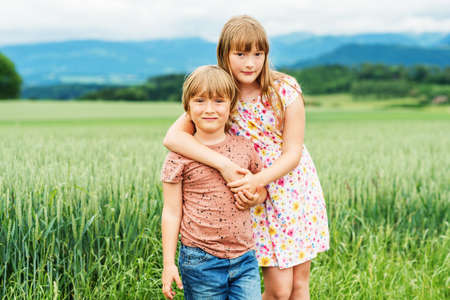 Two adorable kids playing together in summer wheat fieldの写真素材