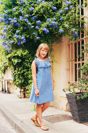 Pretty little girl tourist on the streets of Provence, Wearing blue gingham dress and backpack. Travel with children concept. Image taken in Arles, Franceの写真素材