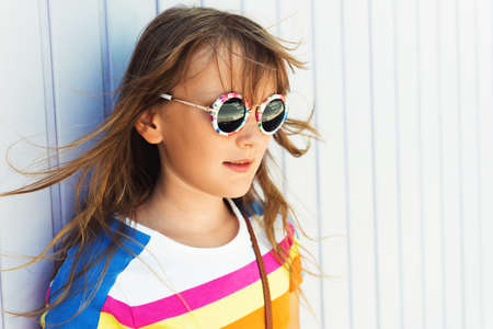 Outdoor close up portrait of adorable little girl wearing modern sunglassesの写真素材