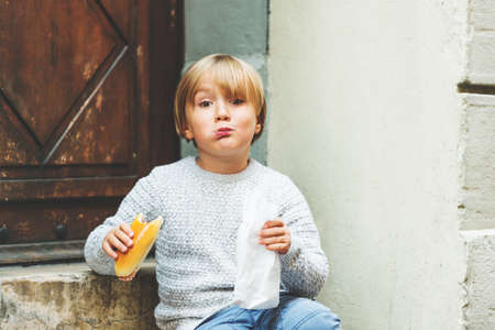 Adorable kid boy eating salami sandwich outsideの写真素材