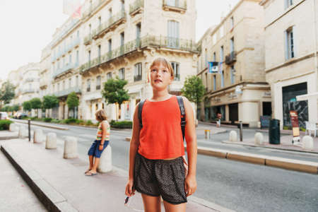 Little girl tourist on the streets of old european city, wearing backpackの写真素材