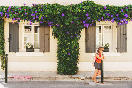 Funny little girl traveler walking on the streets of Provence, wearing backpack. Travel with kids, family vacation on south of France, image taken in Aigues-Mortes, Camargueの写真素材