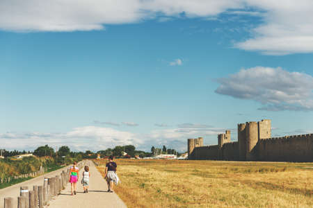Family enjoying promenade around famous fortification wall surrounding Aigues-Mortes city, Camargue, Franceの写真素材
