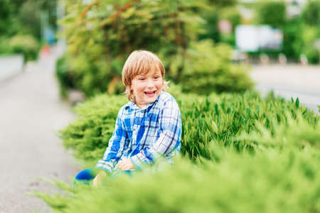 Funny little boy playing outdoors, kid having fun in green park