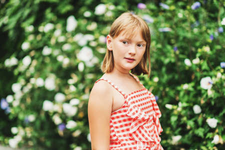 Outdoor portrait of pretty little 9-10 year old girl wearing red gingham dressの写真素材