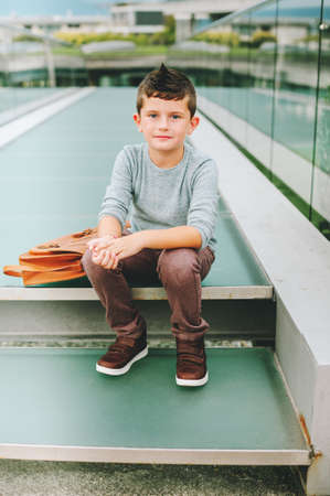 Outdoor portrait of happy young kid boy. Fashion schoolboy resting outside. Back to school conceptの写真素材