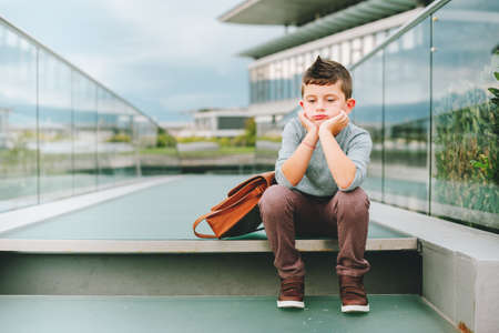 Sad kid boy resting outdoors. Bored little studentの写真素材
