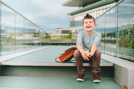 Outdoor portrait of happy young kid boy. Fashion schoolboy resting outside. Back to school conceptの写真素材