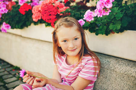 Candid portrait of adorable little 6-7 year old girl holding pink chrysanthemum flowerの写真素材
