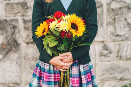 Beautiful bouquet of bright and colorful flowers holding by child's handsの写真素材
