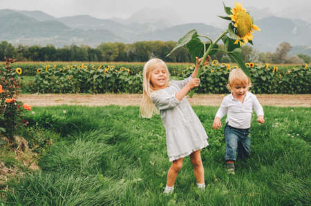 Group of 2 funny kids playing together in flower fields, vacation in countryside with children. Happy active childhood. Family enjoying nature in summerの写真素材