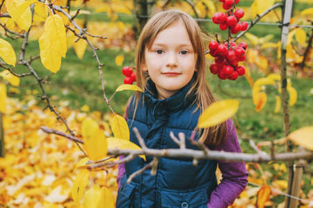 Outdoor portrait of adorable little 5 year old girl in autumn garden, wearing warm blue vestの写真素材