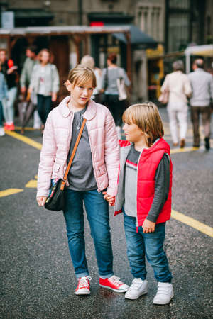 Street fashion for children. Boy and girl wearing padded jackets. Little brother and sister spending...