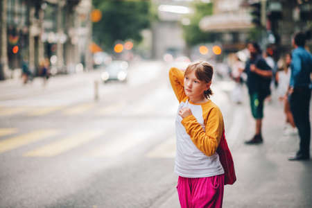 Outdoor portrait of pretty little teenage girl in a city, wearing yellow and white long sleeve baseball t-shirt and bright pink trousersの写真素材