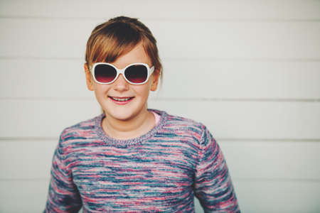 Fashion portrait of pretty little girl wearing sunglasses and purple pulloverの写真素材