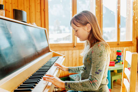 Little girl playing piano at homeの写真素材
