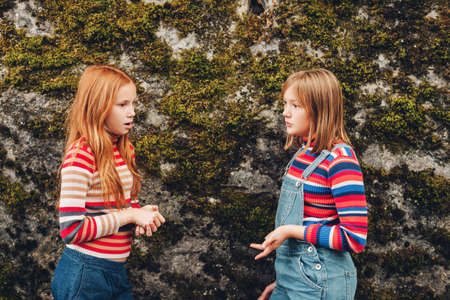Two friends having conversation. Fashion preteen girls wearing roll neck stripe pullovers