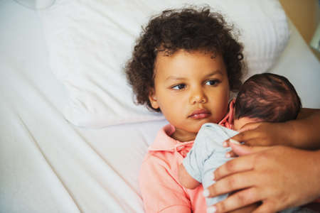 First meeting of adorable african toddler boy and his newborn brother in a prenatal hospital