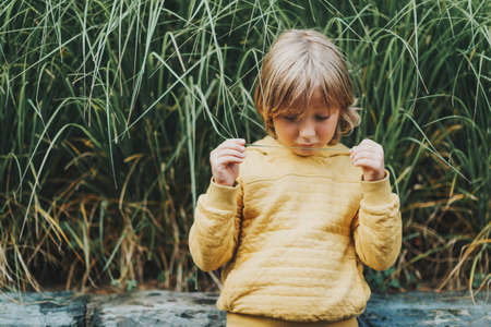Outdoor fashion portrait of cute little boy wearing yellow hoody sweatshirtの写真素材