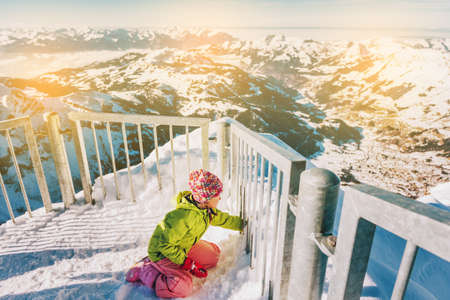 Kid girl playing with snow on the top of the mountain, winter vacation with children, family activities in Alps. Image taken in Glacier 3000, canton of Vaud, Switzerlandの写真素材