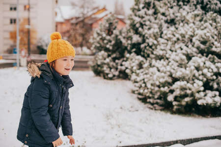 Outdoor portrait of young 6 year old boy wearing warm jacket and boots, enjoying winter time