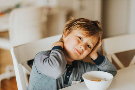 Cute little boy eating his cereals with milk for breakfast
