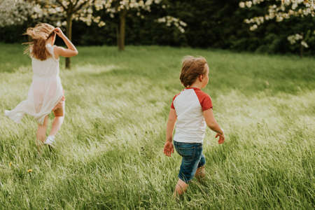 Two adorable kids playing together in spring garden on a very windy day, family spending time outdoorsの写真素材