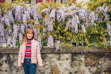 Spring portrait of adorable 9-10 year old kid girl posing in wisteria flowersの写真素材