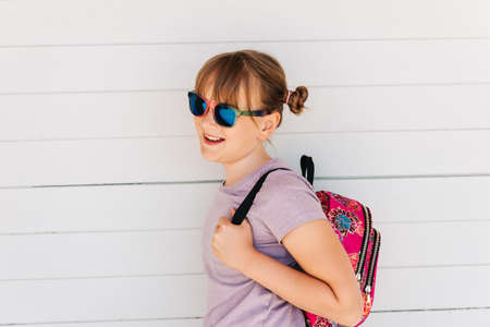 Portrait of funny preteen kid girl, wearing sunglasses, holding backpackの写真素材