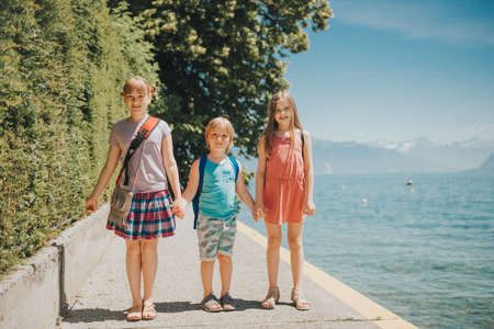 Group of 3 cute kids playing by the lake on a nice sunny day. Image taken on Lake Geneva, Lausanne, Switzerlandの写真素材