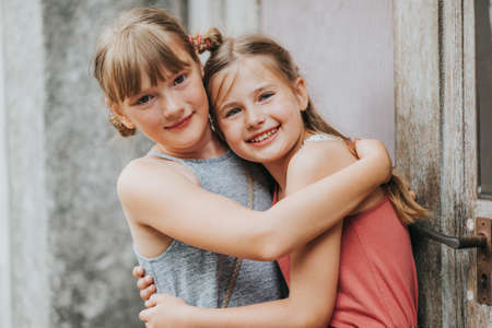 Summer portrait of two adorable kid girls hugging each otherの写真素材