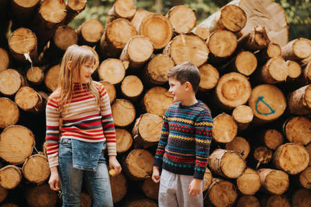 Cute kids playing together in a spring forest next to wooden logsの写真素材
